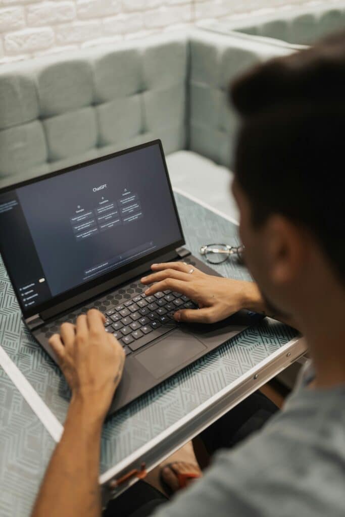 Man using a laptop with a technology interface screen in a modern setting.