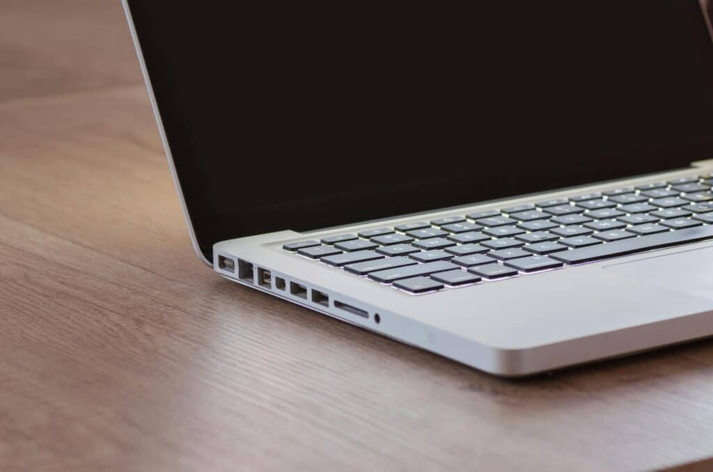 Close-up of a sleek silver laptop with a backlit keyboard on a wooden desk, perfect for tech themes.